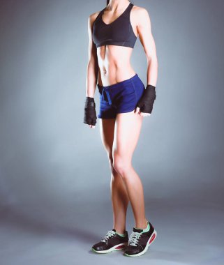 Koyu arkaplanda dambıllarla egzersiz yapan genç bir kadın..