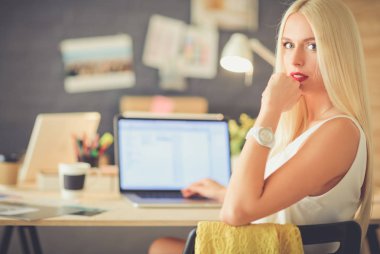 Moda tasarımcıları stüdyoda çalışıyor. Masanın üzerinde oturuyorlar..