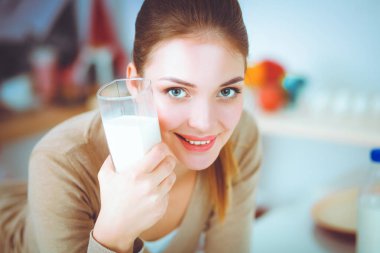 Gülümseyen çekici kadın mutfağın içinde kahvaltı yapıyor.