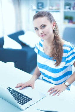 Elinde evrakları olan kadın masanın üstünde oturuyor.