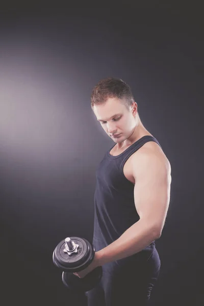 Красивый мускулистый мужчина работает с гантелями — стоковое фото