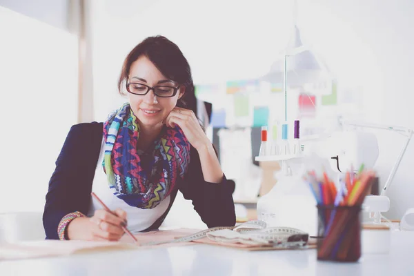 Beautiful fashion designer sitting at the desk in studio . — Stock Photo, Image