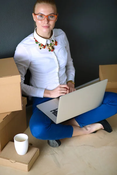Vrouw zittend op de vloer in de buurt van een dozen met laptop. Zakenvrouw — Stockfoto
