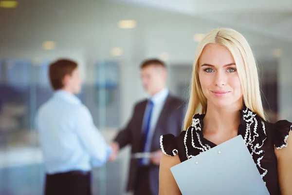 Portret van jonge zakenvrouw in functie met collega 's op de achtergrond . — Stockfoto