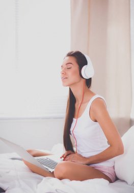 Genç güzel kadın yatakta müzik.