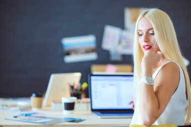 Moda tasarımcıları stüdyoda çalışıyor. Masanın üzerinde oturuyorlar..