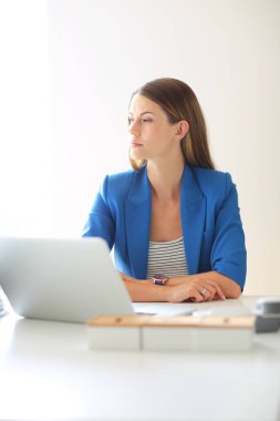 Elinde evrakları olan kadın masanın üstünde oturuyor.