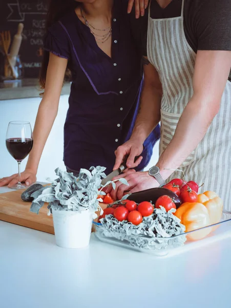 Jonge man snijden groenten en vrouw stond in de keuken — Stockfoto