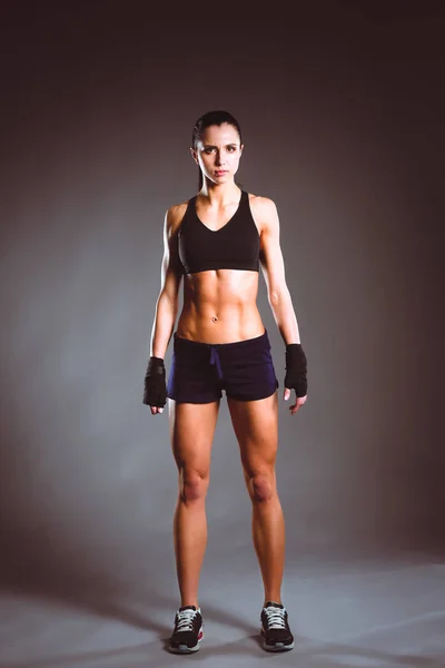 Musculosa joven posando en ropa deportiva sobre fondo negro — Foto de Stock