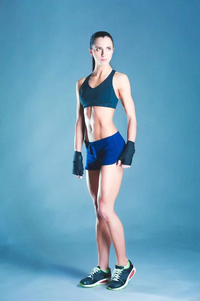 Мускулистая молодая женщина позирует в спортивной одежде на черном фоне — стоковое фото