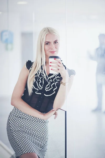 Ofiste bir fincan kahve ayakta tutan işkadını .