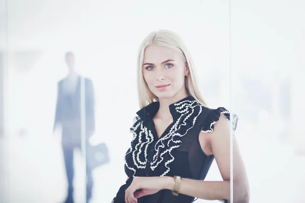 Business woman standing in foreground in office .