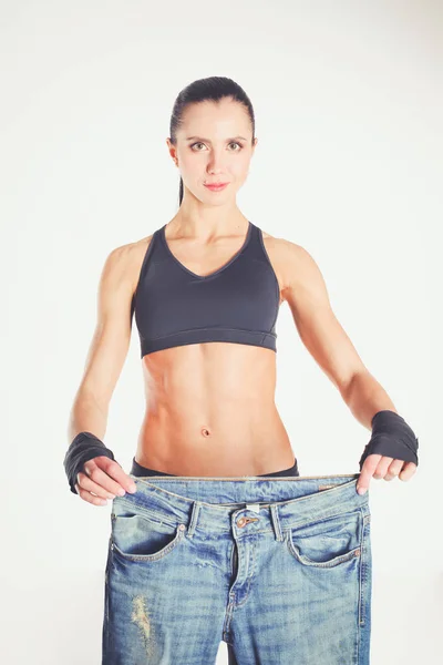 Jonge fitness vrouw tonen dat haar oude jeans . — Stockfoto
