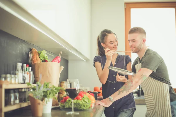 Bir çift evdeki mutfaklarında birlikte yemek pişiriyor.