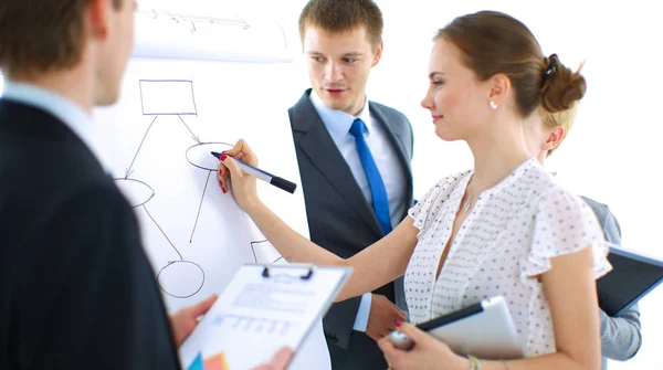 Businesswoman writing on flipchart while giving presentation to colleagues in office — Stock Photo, Image