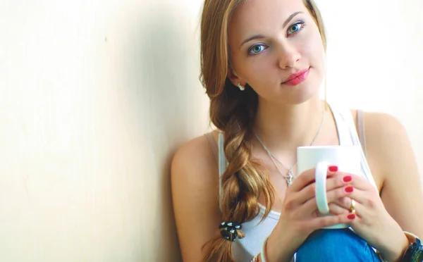 Hermosa mujer sentada en el suelo y sosteniendo una taza —  Fotos de Stock