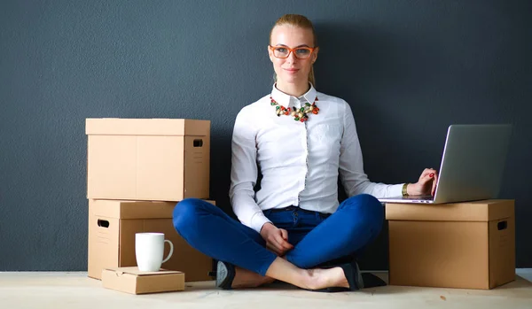 Woman sitting on the floor near a boxes  with laptop — Stock Photo, Image