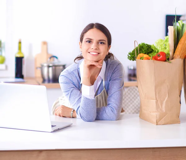 Portret van een lachende vrouw die in haar keuken zit te koken — Stockfoto