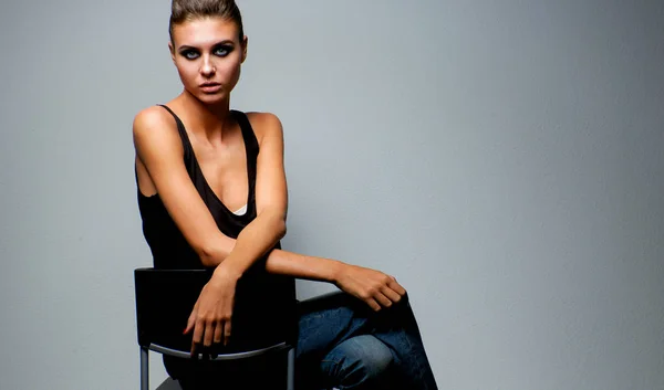 Beautiful woman  sitting  a chair, isolated on gray background Stock Photo