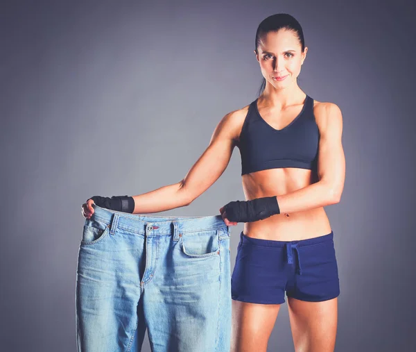 Mladá fitness žena ukazuje, že její staré džíny — Stock fotografie