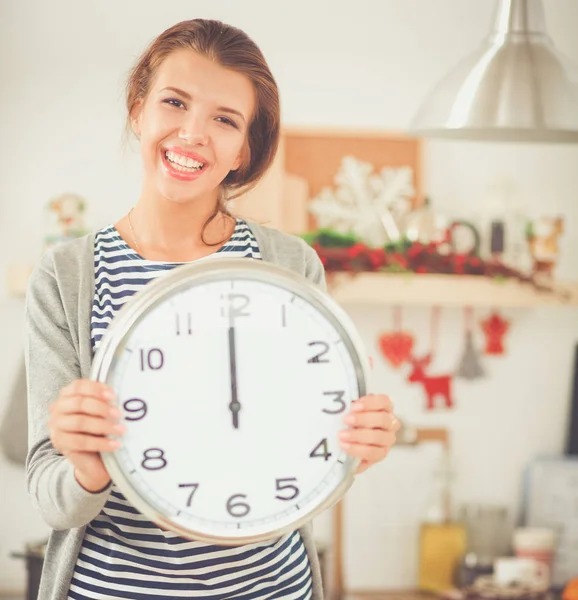 Happy young woman showing clock in christmas decorated kitchen — Stock Photo, Image