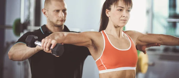 Schöne Frau im Fitnessstudio beim Training mit ihrem Trainer — Stockfoto