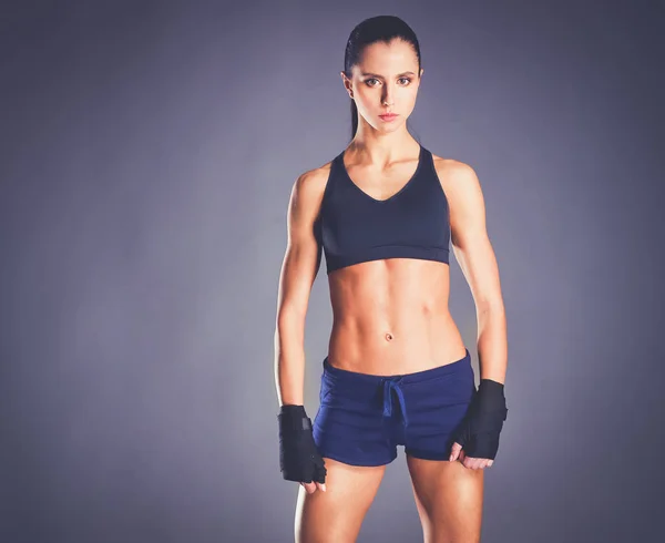 Muscular young woman posing in sportswear against black background — Stock Photo, Image