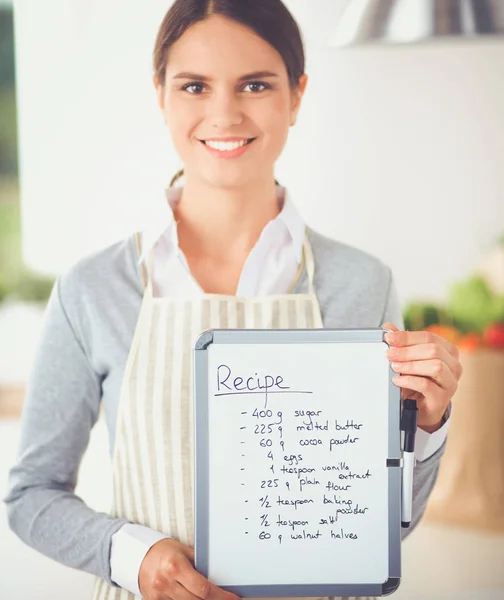 Kvinna i köket hemma, stående nära skrivbord med mapp — Stockfoto