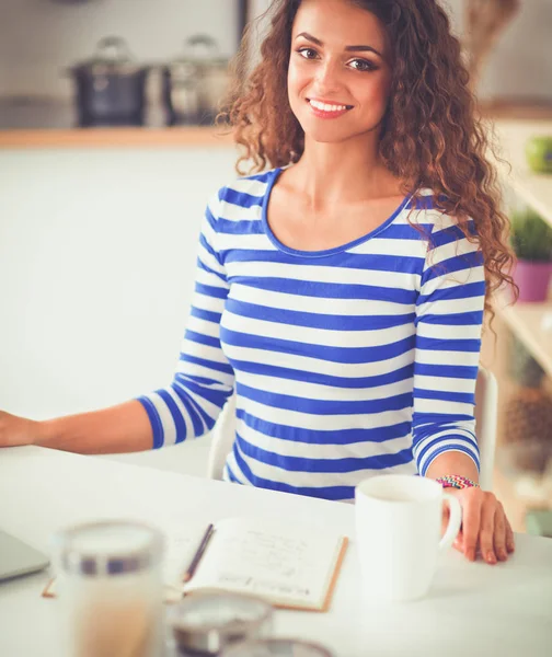 Femme dans la cuisine à la maison, debout près du bureau avec dossier — Photo