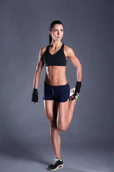 Mięśni młoda kobieta pozowanie w sportowej na czarnym tle. — Zdjęcie stockowe
