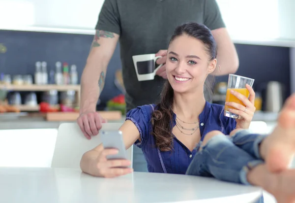 Pareja feliz usando smartphone sentado en la cocina — Foto de Stock