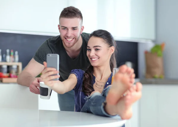 Pareja feliz usando smartphone sentado en la cocina — Foto de Stock