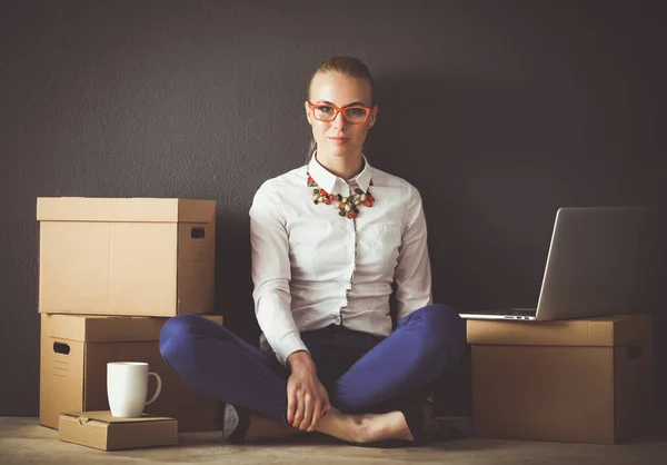 Woman sitting on the floor near a boxes with laptop . Businesswoman — Stock Photo, Image