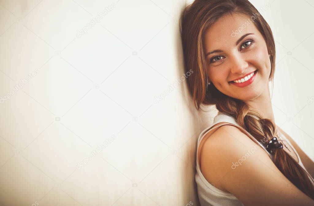 Young woman sitting on the floor near wall . Young woman