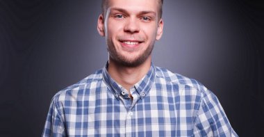 Gri arka plan üzerinde izole gülümseyen genç adam portresi