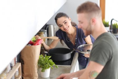 Bir çift evdeki mutfaklarında birlikte yemek pişiriyor.