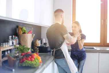 Bir çift evdeki mutfaklarında birlikte yemek pişiriyor.