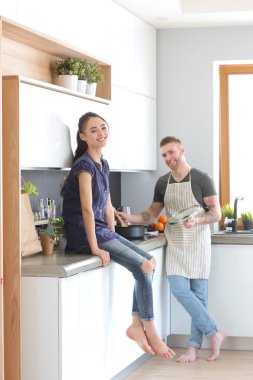 Bir çift evdeki mutfaklarında birlikte yemek pişiriyor.