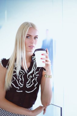 Ofiste bir fincan kahve ayakta tutan işkadını .