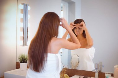 Çekici genç bir kadın yüzüne krem sürüyor.