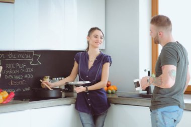 Bir çift evdeki mutfaklarında birlikte yemek pişiriyor.