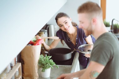 Bir çift evdeki mutfaklarında birlikte yemek pişiriyor.