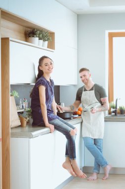 Bir çift evdeki mutfaklarında birlikte yemek pişiriyor.
