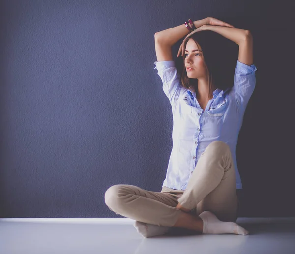 Mujer joven sentada en el suelo cerca de la pared oscura —  Fotos de Stock