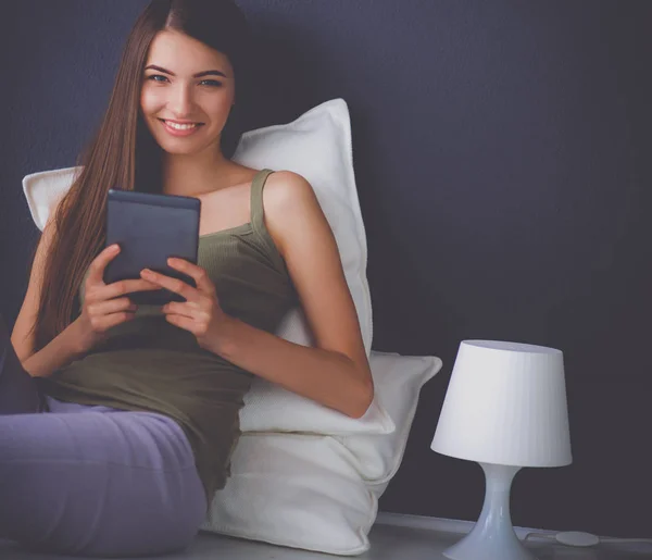 Mujer morena bonita sentada en el suelo con una almohada y mesa de avión — Foto de Stock