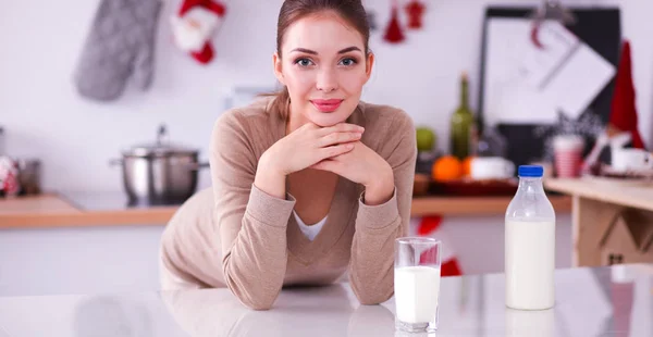 Sonriente joven bebiendo leche, parada en la cocina —  Fotos de Stock
