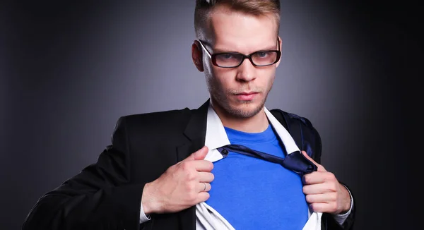 Young businessman acting like a super hero and tearing his shirt, isolated on gray background — Stock Photo, Image