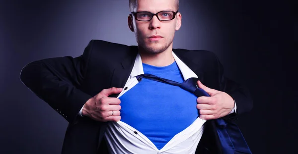 Joven hombre de negocios actuando como un súper héroe y rasgando su camisa, aislado sobre un fondo gris — Foto de Stock