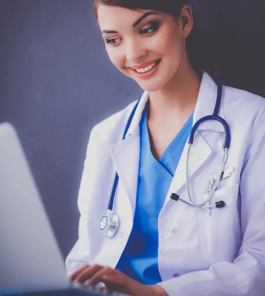 Médico femenino trabajando sentado sobre fondo gris — Foto de Stock