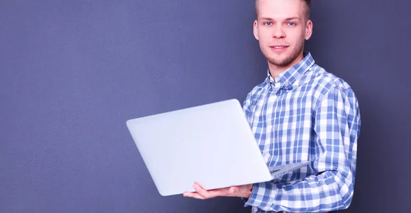 Портрет впевненого молодого чоловіка з ноутбуком, що стоїть над сірим тлом — стокове фото